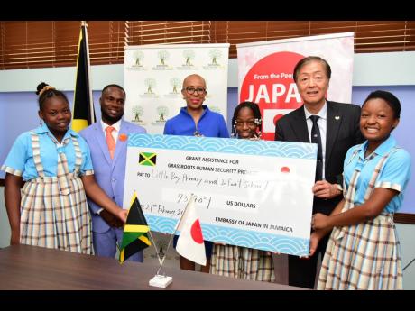 Fayval Williams, minister of education and youth (third left), and Japan Ambassador Yasuhiro Atsumi (second right) hand over a symbolic cheque to fund a new school bus to (from left) Ackecia Gayle, head girl of Little Bay Primary and Infant schools; Keron 