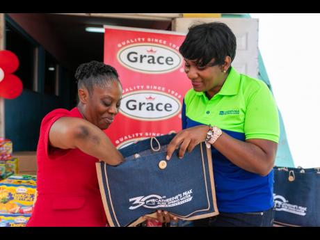 Talented Young Minds Preschool Principal, Nneka Morris, takes a peek inside one of the gift bags donated by Catherine’s Peak during the Grace Foods donation to the school on February 14 to commemorate GraceKennedy Group’s 101st anniversary. 