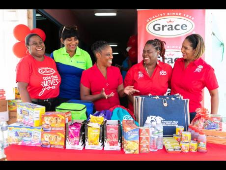 Morris (center) expresses her gratitude to representatives from Grace Foods when the team made a donation of Grace food items and cases of Catherine’s Peak bottled spring water to the early childhood institution. Representatives from Grace Foods are (fro