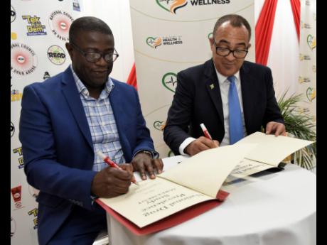 Health and Wellness Minister Dr Christopher Tufton (right) and National Health Fund (NHF) CEO Everton Anderson put pen to paper in a symbolic signing between the ministry and the NHF for a national drug prevalence study. The signing took place at the healt