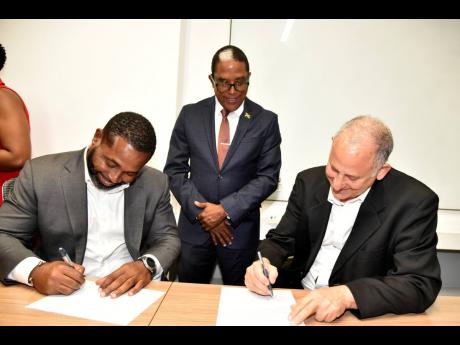 From left: CEO and founder of Caribshopper, Kadion Preston, signs a contract with CEO, Jamaican Teas Limited and President of Jamaica Manufacturers and Exporters Association (JMEA), John Mahfood, during the JMEA-Caribshopper partnership signing ceremony on