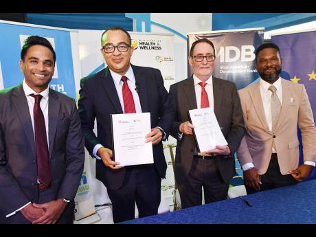 Dr Christopher Tufton (second left), minister of health and wellness, and Dr John Parry (second right), clinical director of The Phoenix Partnership (TPP) UK, show off the contract for the implementation of the electronic health records system at the Spani