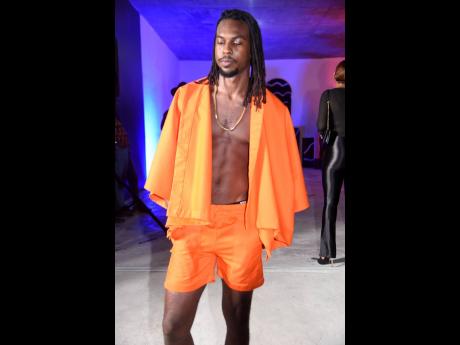 Visual artist, Joshua Solas, walk down the runway in a fire-orange poncho and patch pocket shorts.