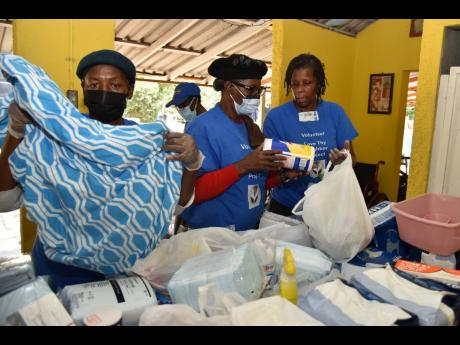 From left: Claudette Clarke, Inez Watson and Christine Campbell pack small care packages for residents of the Eira Schader Home for the aged. The packages were donated by the Love Thy Neighbour Organisation.