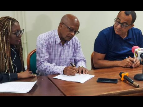 In this March 2022 photo, Dr Jeffrey East, general surgeon, and new chairman of the Oversight Committee for the Cornwall Regional Hospital Restoration Project (centre), signs the MOU agreeing to the Terms of Reference shortly after Minister of Health and W
