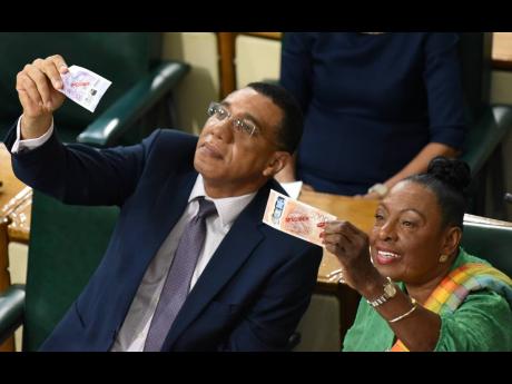 Prime Minister Andrew Holness (left) and Olivia Grange, minister of culture, gender, entertainment and sports, look at the new Jamaican banknotes that will soon go into circulation as Finance Minister Dr Nigel Clarke made his Budget presentation on Tuesday