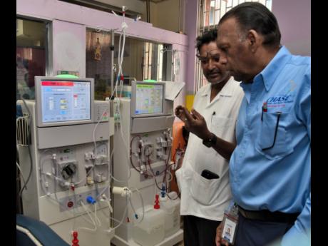 Dr Basil Babolal (left), consultant nephologist at the Kingston Public Hospital (KPH), explains how the haemodialysis machine works to Wilford ‘Billy’ Heaven, CEO of the CHASE Fund, while touring the institution’s renal unit following the handing ove