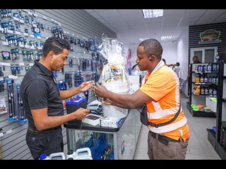 Sales Representative at Automotive Art, Christopher Peart (left), assists customer Kevin Mellad with his purchase at the Automotive Art store located at 50 Hagley Park Road.