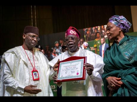 President-Elect Bola Tinubu, centre displays his certificate, accompanied by his wife Oluremi Tinubu, right, and chairman of the Independent National Electoral Commission Mahmood Yakubu, left, at a ceremony in Abuja, Nigeria Wednesday, March 1.