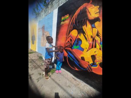 Two youngsters admire a portrait of reggae legend Bob Marley, which was painted by James ‘Jimmy’ Stewart in August Town.