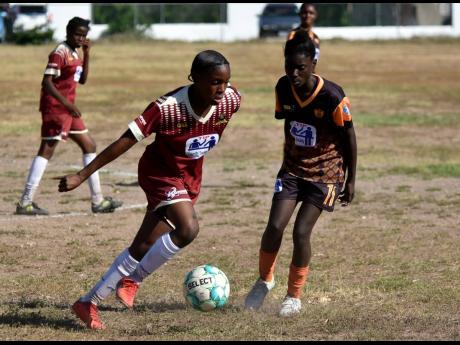 From Left: Denham Town’s Natoya Atkinson goes on one of her mazy dribbles while being tracked by Tivoli High School’s Nathania Morris during their ISSA/TIP Friendly School Girls’ football game at the Tivoli High School playfield yeterday.