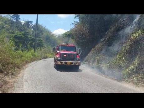 The Jamaica Fire Brigade responds to bushfires along the Junction main road in St Andrew on Monday.