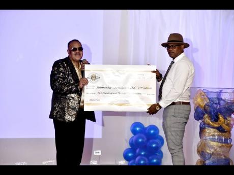From left: Sephon Mair presents a symbolic cheque of $225,000.00 to Stephen Josephs of Sanmera as a donation towards care and upkeep for teenage burn victim, Adrianna Laing.