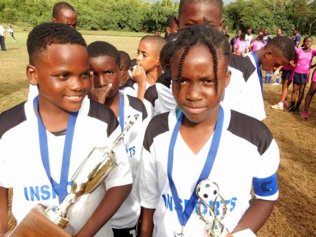 Pembroke Hall Primary School captain Tianna Grant (right) poses for a photo with teammate Antowan Mullings after the team won the Insports All-Island Primary Schools’ football title at the Discovery Bay Community Centre on Friday. 