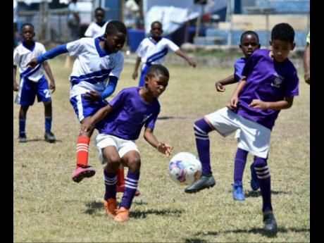 
Sts Peter and Paul players surround a ball during a Youth Football League Junior Cup Under-9 game against St Aloysius on their way to the final at the Constant Spring Football field yesterday.