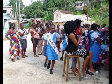 In this 2015 photo community members applaud as contestants in the Miss Cacoon Primary School parade in the Dias community square in Hanover at the sash ceremony.