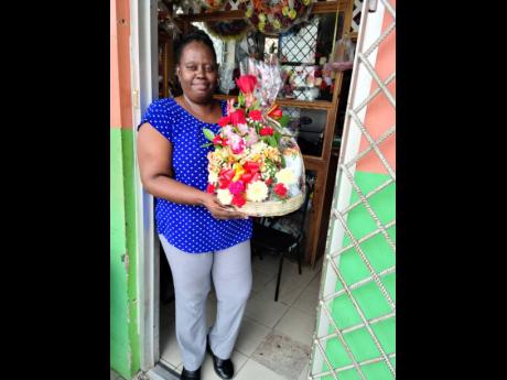 Peaches Brown stands at the door of her establishment, holding a fruit basket made for a client.