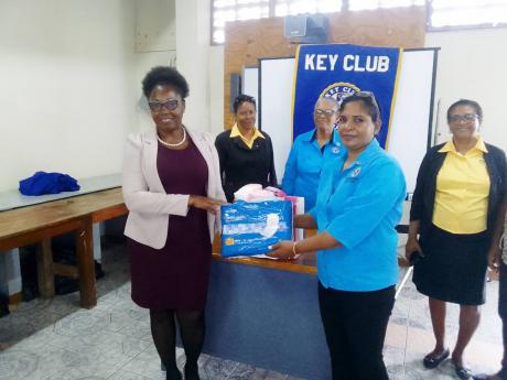 President of the Kiwanis Club of Negril Point, Indira Mangarweise (right), presents a box of sanitary napkins to  Judith Brown, guidance counsellor at Ruseas High School, as other Kiwanians look on.