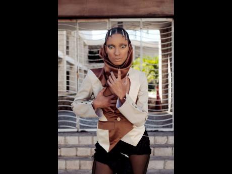 A camo brown and beige jacket with a scarf and draped back is amplified with an asymmetric sabre mini-skirt with zipper detail and distressed rosette manipulation in pistol black.