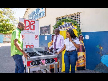 Assistant brand manager for Malta Cavell Robinson (right), D&G Foundation Accountant Dennis Beckford and Riverton Meadows Early Childhood Centre Principal Junior Rowe (centre) admire the fully assembled stove.