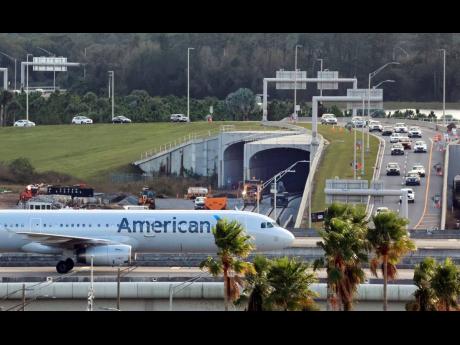 An American Airlines plane taxis by at the Orlando International Airport Intermodal Terminal, December 14, 2021.
