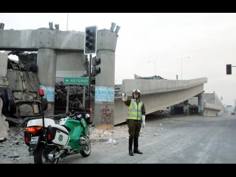 In this February 27, 2010 photo, a  police officer controls the traffic aside of an elevated highway that collapsed in Santiago following a powerful earthquake in central Chile.