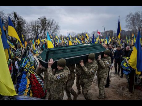 Ukrainian servicemen carry the coffin of their comrade Andrii Neshodovskiy during the funeral ceremony at the cemetery in Kyiv, Ukraine, Saturday.