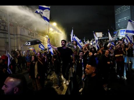 Israeli police use a water cannon to disperse demonstrators blocking the freeway during a protest against plans by Prime Minister Benjamin Netanyahu’s government to overhaul the judicial system in Tel Aviv.