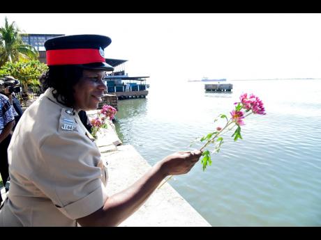 Inspector Cynthia Graham, from the City Centre Police Station in downtown Kingston, tosses flowers into the Kingston Harbour on Saturday as part of the observance of March 25 as National Day of Remembrance of the Victims of Slavery. 