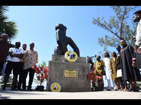 Culture Minister Olivia Grange and members of the National Council on Reparation paying tribute to the local victims of slavery and the slave trade in downtown Kingston on Saturday.
