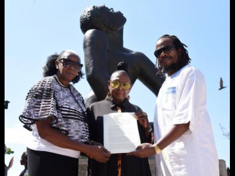 From left: Laleta Davis-Mattis, chairman of the National Council on Reparation; Culture Minister Olivia Grange; and Stephen Golding, president of the Universal Negro Improvement Association, hold the proclamation declaring March 25 as National Day of Remem