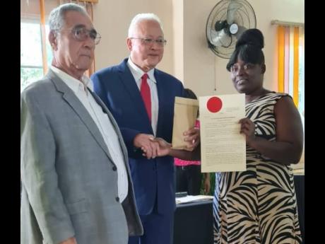 Newly commissioned Clarendon Justice of the Peace Samantha Ackas receives her instrument of appointment and seal from Justice Minister Delroy Chuck while Custos William Shagoury looks on.