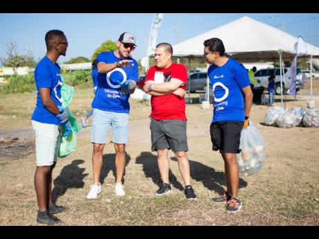 Managing Director of Caribbean Cement Company Limited, Yago Castro (second left), makes a point to Senator Matthew Samuda (second right), minister without portfolio in the Ministry of Economic Growth and Job Creation, at a beach clean-up at the Sirgany Bea