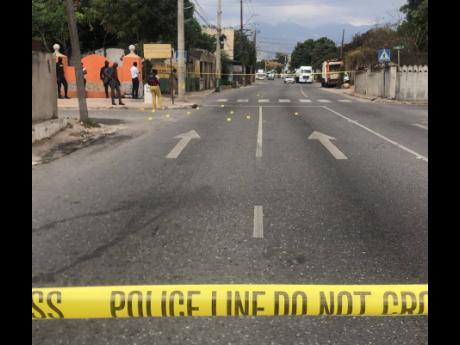 Crime scene investigators comb a section of Maxfield Avenue in St Andrew after a recent drive-by shooting. The male victim’s wounds were not considered life-threatening.
