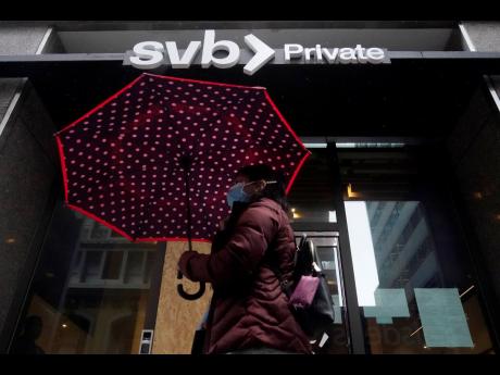 AP 
A pedestrian carries an umbrella while walking past a Silicon Valley Bank Private branch in San Francisco on Tuesday, March 14.