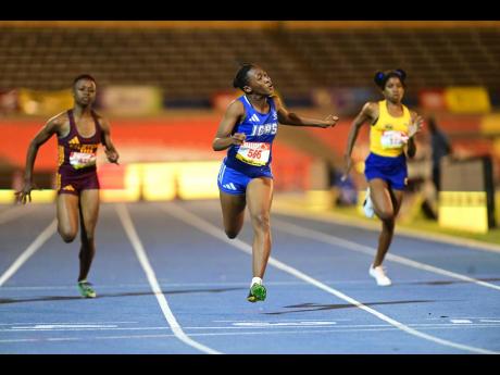 Kayla Johnson (centre) of Immaculate Conception High  wins the Class Four Girls’ 100 metres final at the National Stadium on Wednesday night.
