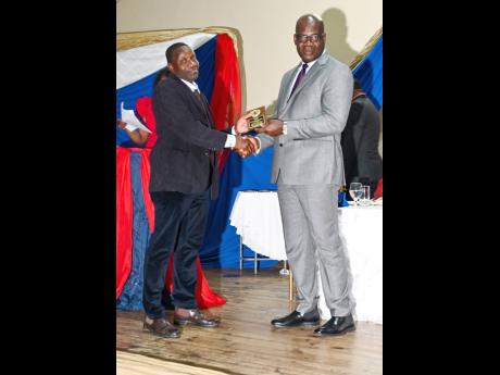 Detective Constable Desmond Campbell (left), collects his awards from Deputy Commissioner of Police Fitz Bailey. Campbell was declared the top performer in the Criminal Investigative Branch of the Westmoreland Police Division, on March 25. 