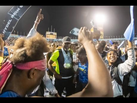 Hydel High’s coach Corey Bennett (centre) celebrates the school’s first Girls’ Champs triumph with members of his track and field team.