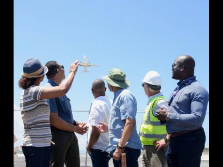 From left: St James Central Member of Parliament (MP) Marlene Malahoo Forte waves as a flight takes off during a tour of Sangster International Airport runway expansion project in Montego Bay, St James, on Saturday. Also photographed are Prime Minister And