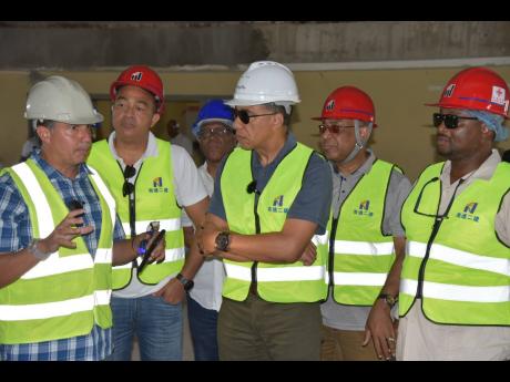 Prime Minister Andrew Holness (centre) listens attentively to Vivian Gordon (left), project manager overseeing rehabilitation work at Cornwall Regional Hospital. Others listening (from second left) are Dr Christopher Tufton, minister of health and wellness