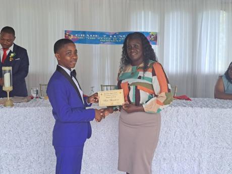 Miguel Sterling, a grade-seven student of the Muschett High School in Wakefield, Trelawny, receives an award for Best Attendance from Kereese Holness, the grade-seven coordinator for Muschett High School, during the school’s fifth annual grade-seven lunc