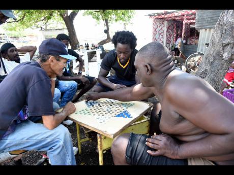 Fishermen enjoying a game of Chinese checkers at the Rae Town Fishing Village in Kingston on Friday.