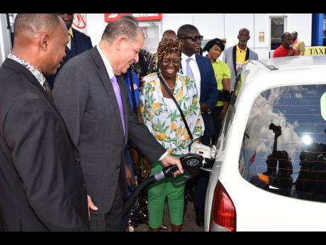 Transport Minister Audley Shaw (second left) pumps gas for a taxi operator who participated in the Transport Operators Development Sustainable Services (TODSS) health, wealth and safety expo at the FESCO gas station on Beechwood Avenue in St Andrew last Th