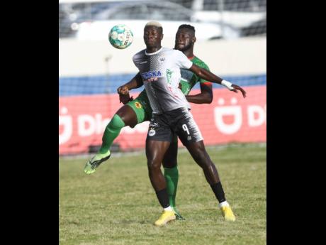 Cavalier’s  Collin Anderson (left) is tackled by Humble Lion’s Ricardo Campbell during their Jamaica Premier League encounter at the  Ashenheim Stadium, Jamaica College yesterday.