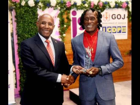 Aubyn Hill (left), Minister of Industry, Investment and Commerce, hands Garth Bowers the first place award for Entrepreneurship, for his business ‘production plan’ in the community of Greenwich Town. Occasion was the Jamaica Social Investment Fund’s 
