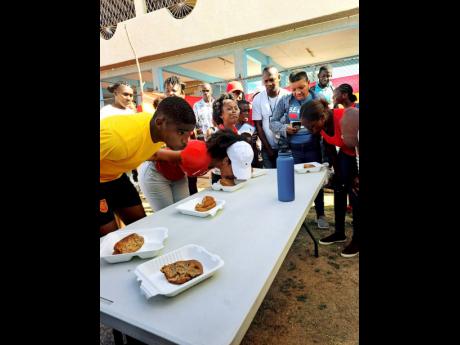 Police personnel compete in a bun eating contest at a fun day held at the Spanish Town Prison Oval, on Easter Monday, April 10.