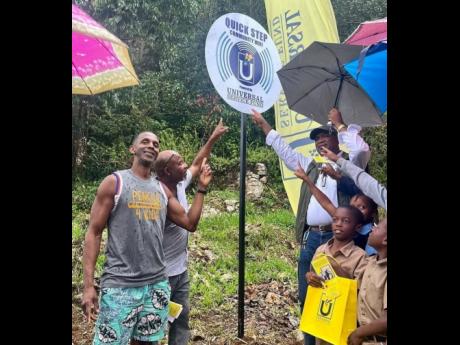 Randy Griffiths, founder of international charity Pencils4Kinds, St Elizabeth North Eastern Member of Parliament Delroy Slowley and students from Quickstep Primary School pointing to the signage after the Universal Service Fund installed a free public Wi-F