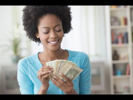 African American woman counting money in living room.