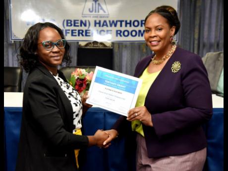 La Sonja Harrison (right) president of the Jamaica Teachers Association (JTA), presents Yanique Salmon (left) with a grant certificate for her tertiary-level studies. Occasion was the JTA Inaugural Basic School Tertiary Education Grant award ceremony which