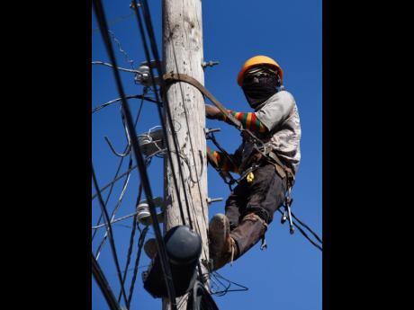 A Jamaica Public Service Company crewman removes wires from a utility pole on  Woodglen Drive to faciliatate the relocation of poles amid a widening of the roadway by the National Works Agency in 2021.